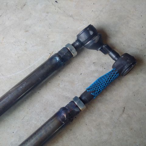 1978 Ford Bronco - Close-up of two automotive tie rod ends, one protected by blue netting.