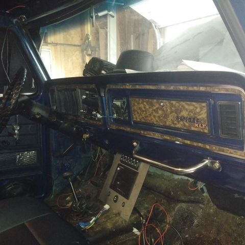 1978 Ford Bronco - The interior of a vehicle shows a dashboard with wood-grain accents and 'Ranger XLT' badging, with exposed wiring.