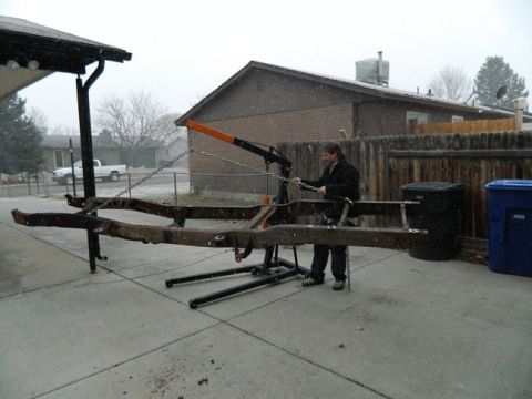 1979 Ford Bronco - A person operates an engine hoist to lift a vehicle frame in a snowy backyard.