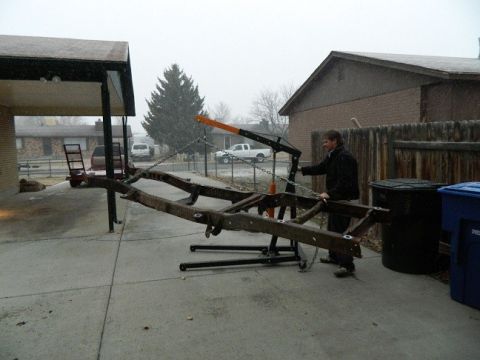 1979 Ford Bronco - A vehicle frame is suspended by an engine hoist outdoors during snowy weather.