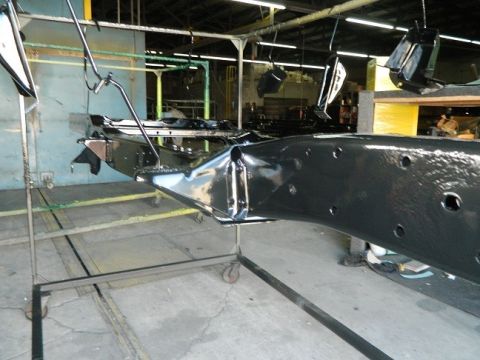 1979 Ford Bronco - A vehicle frame is suspended and undergoing a powder coating process in an industrial setting.