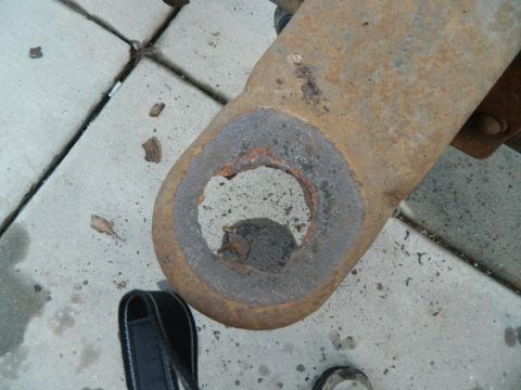 1979 Ford Bronco - Close-up of a heavily rusted metal component with a significant hole, resting on a concrete surface.