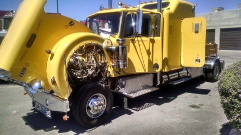 1979 Ford Bronco - A yellow semi-truck is parked with its hood open, revealing the engine compartment.