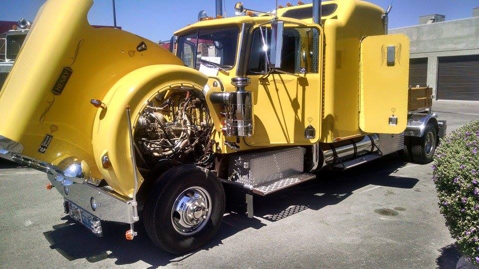 Yellow semi-truck with hood open, exposing engine and wiring. Chrome accents visible
