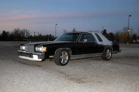 1985 Mercury Grand Marquis - A black and silver 1985 Mercury Grand Marquis coupe is parked outdoors under a twilight sky.