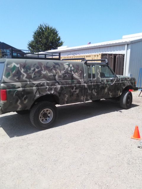 1991 Ford Bronco - This 1991 Ford F-150 pickup truck is painted in camouflage and equipped with a camper shell and roof rack.
