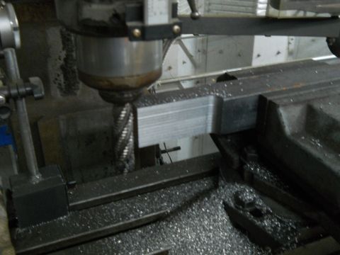 1992 Ford Bronco - A milling machine is actively cutting a metal component, with numerous metal shavings scattered around the workspace.