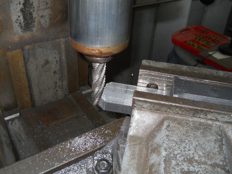 1992 Ford Bronco - A milling machine is actively cutting a metal component, with metal shavings visible on the machine bed.