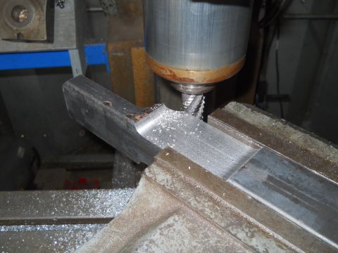 1992 Ford Bronco - A milling machine is used to cut a metal part, with metal shavings accumulating around the workpiece.