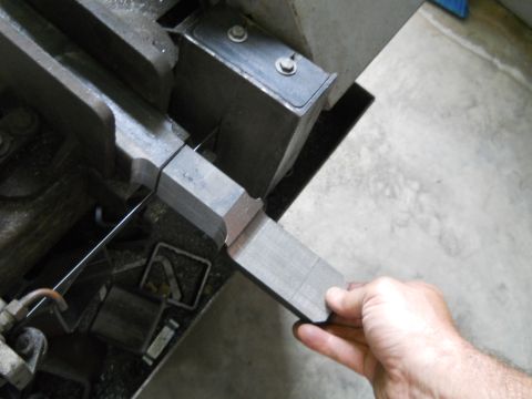 1992 Ford Bronco - A metal piece is being cut with a band saw in a workshop setting.
