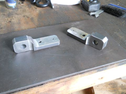 1992 Ford Bronco - Two machined metal parts are shown on a workbench surface, with tools visible in the background.