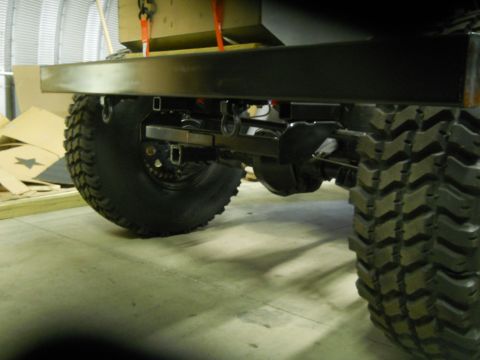 1992 Ford Bronco - Close-up view of the rear axle and chunky tires on a vehicle, with a metal bumper overhead.