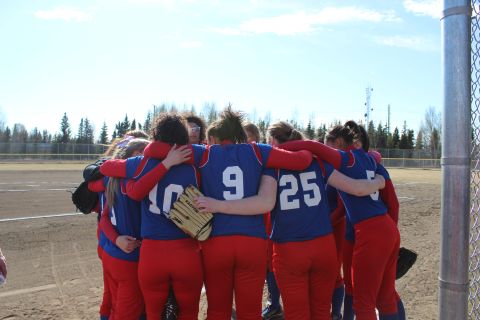 1990 Chevrolet Suburban - A team huddles together on a baseball field under a bright sky.