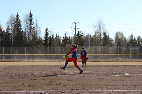 1990 Chevrolet Suburban - A softball pitcher throws a pitch during a game on a sunny day.