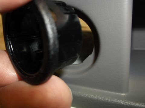 1999 Mercury Grand Marquis - Close-up of a hand removing a black interior trim piece from a gray dashboard panel.