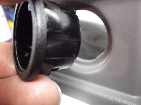 1999 Mercury Grand Marquis - A person holds a black plastic trim piece near a circular opening in a gray car interior panel.
