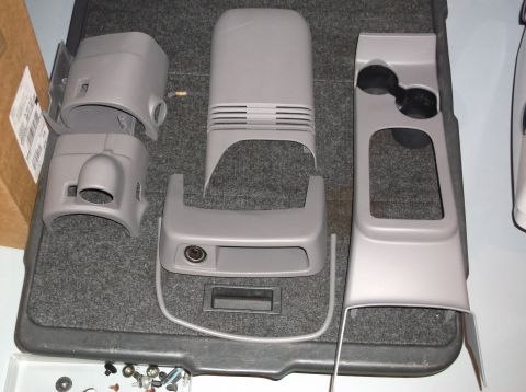 1999 Mercury Grand Marquis - Disassembled center console components, including cup holders and trim pieces, are displayed on a gray carpeted base.