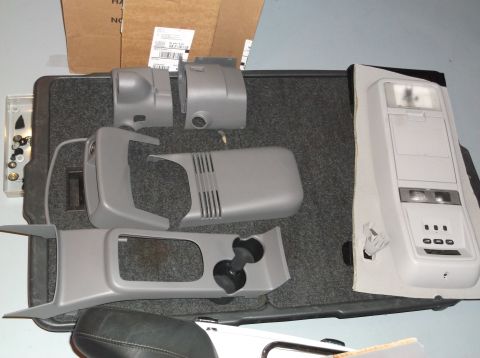 1999 Mercury Grand Marquis - Various interior trim parts, likely for a car's center console and overhead lighting system, are laid out on a carpeted surface.