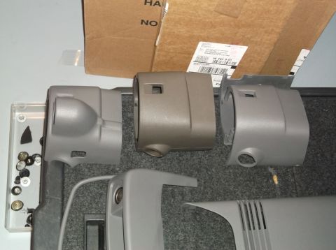 1999 Mercury Grand Marquis - Various plastic parts, likely for a vehicle's steering column, are displayed with hardware and a box in the background.