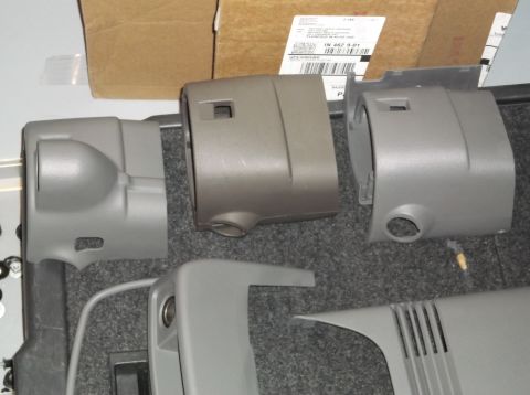 1999 Mercury Grand Marquis - Several plastic steering column covers are displayed on a carpeted surface, with a cardboard box in the background.
