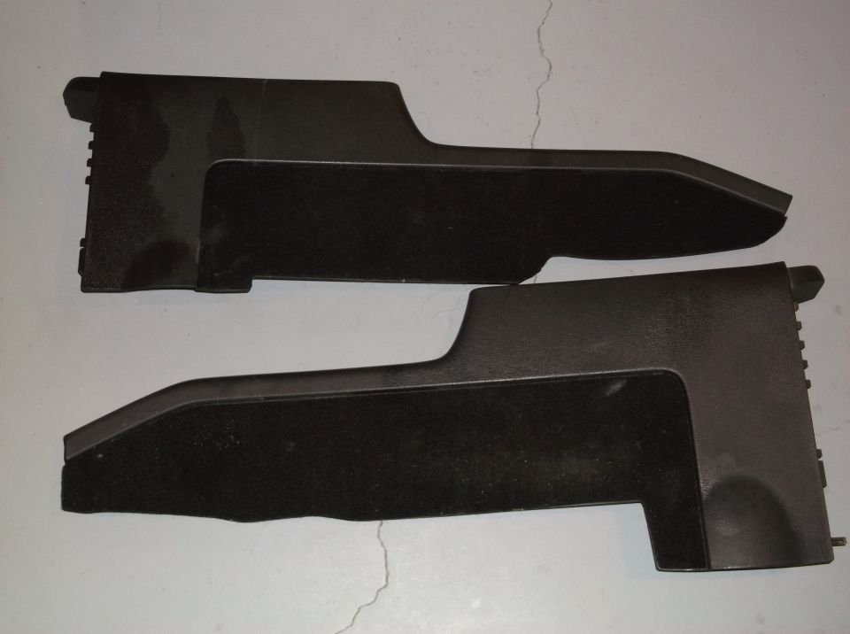 Two black plastic console trim pieces with carpeted inserts