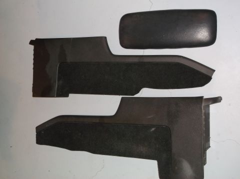 1999 Mercury Grand Marquis - Black plastic car console trim pieces and armrest pad are laid out on a light-colored surface.