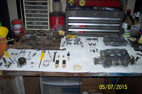1973 Ford F-250 - Various carburetor components and tools are organized on a workbench for a rebuild project.