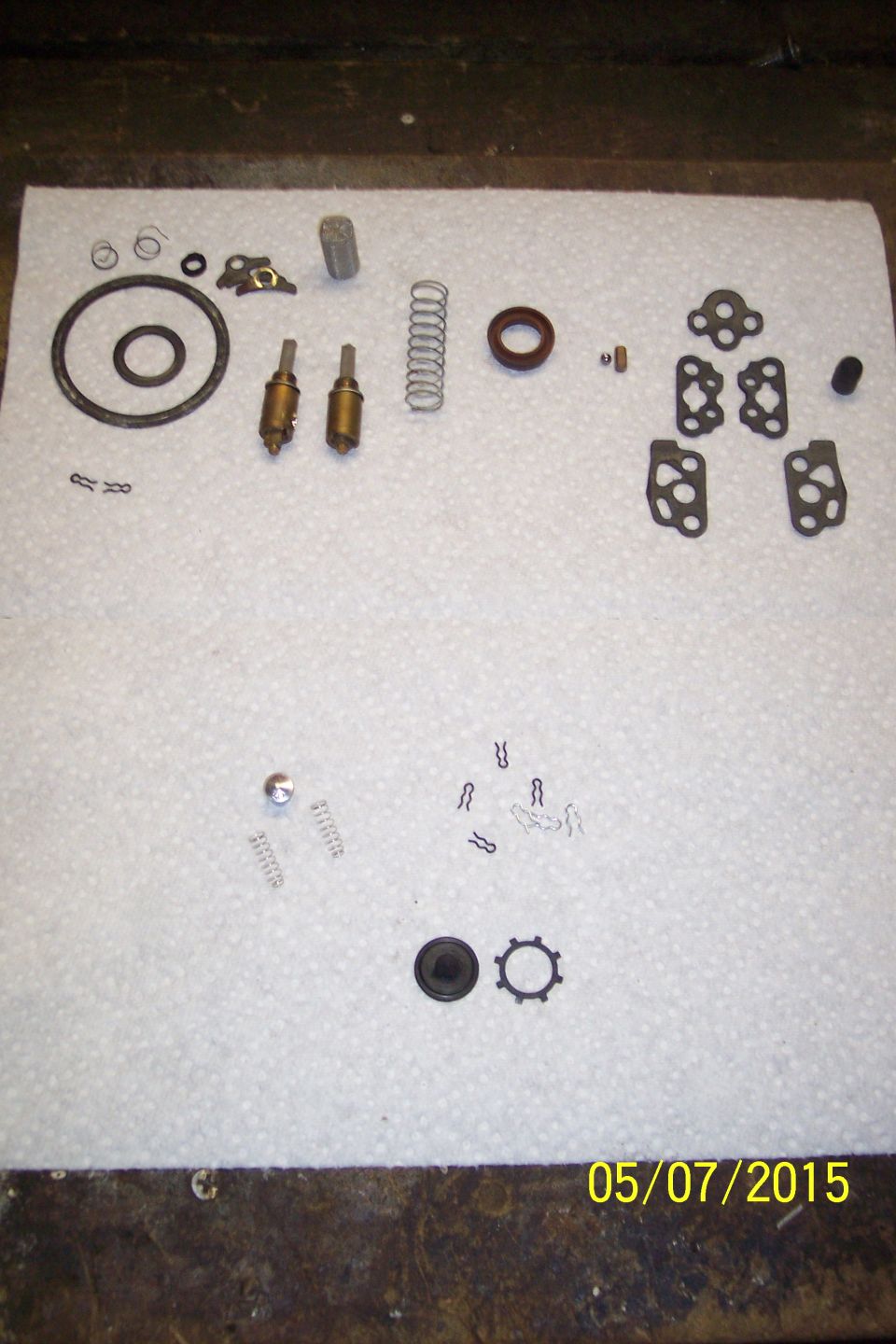 Carburetor rebuild kit parts laid out on a white paper towel