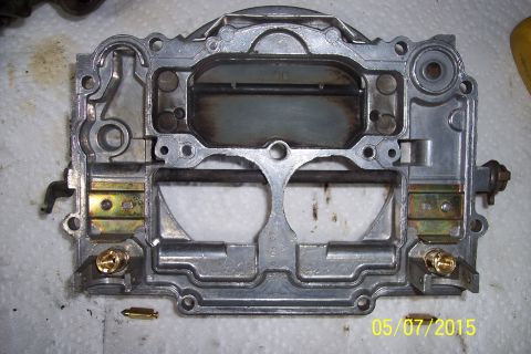 1973 Ford F-250 - Close-up view of a carburetor base, showing internal passages and brass fittings, possibly during a rebuild process.