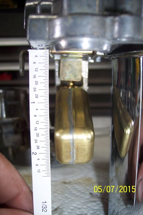 1973 Ford F-250 - Close-up of a carburetor float being measured with a ruler, indicating a part measurement for a rebuild.