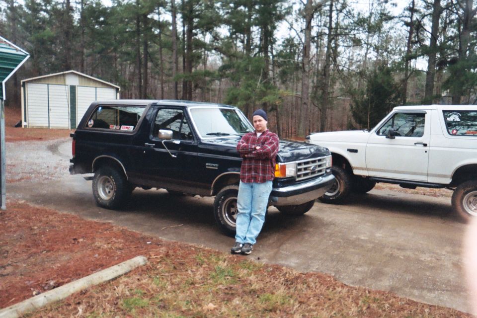 Black 1988 Ford Bronco with a man standing in front, white Bronco behind