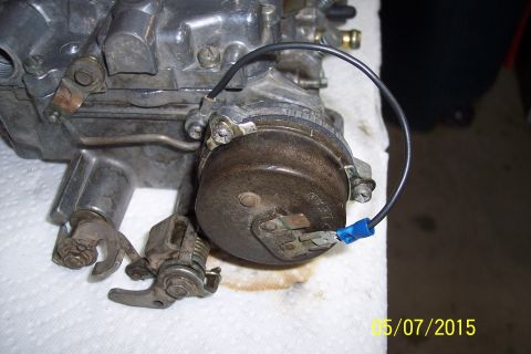 1973 Ford F-250 - Close-up view of a carburetor, likely undergoing a rebuild, with a blue wire connector attached.