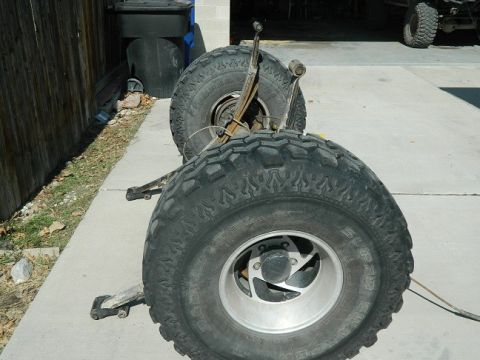 1979 Ford Bronco - The rear axle and tires of a vehicle are shown, with another vehicle visible in the background.