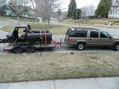 1979 Ford Bronco - A brown 1979 Ford Bronco is transported on a trailer, towed by a tan SUV.