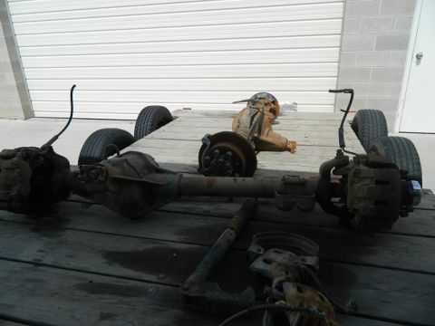 1979 Ford Bronco - Vehicle axles and tires are loaded onto a trailer, likely for transport or storage.