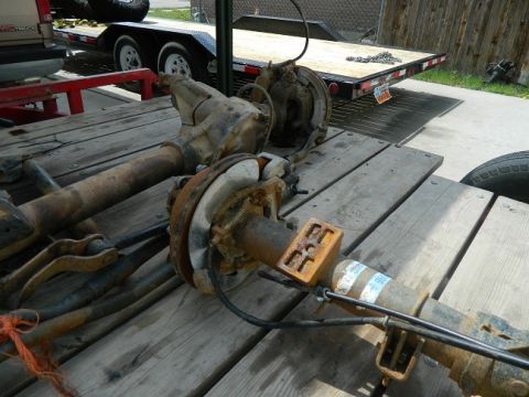 1979 Ford Bronco - Two old axles are laid out on a trailer, showing signs of wear and tear.
