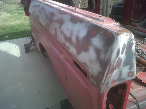 1979 Ford Bronco - This red vehicle quarter panel is undergoing repair, with visible primer and body filler patches.