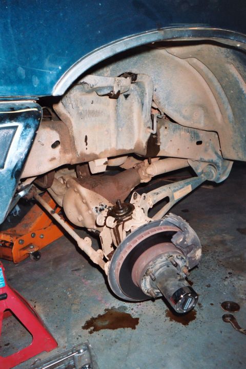 1988 Ford Bronco - The vehicle's front suspension and brake assembly are exposed, with fluid leaking onto the garage floor.