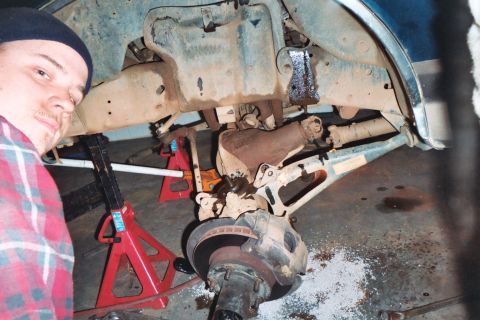 1988 Ford Bronco - A person stands by the undercarriage of a lifted truck, which is supported by jack stands.