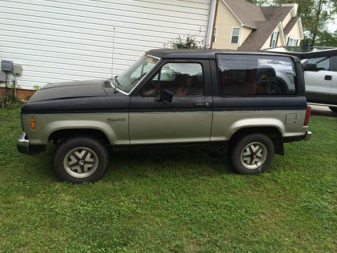 1988 Ford Bronco II - This two-tone 1988 Ford Bronco II is parked on a grassy lawn next to a house.