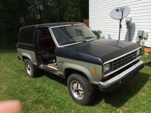 1988 Ford Bronco II - This SUV has a two-tone paint scheme and its driver's side door is ajar, revealing the interior.