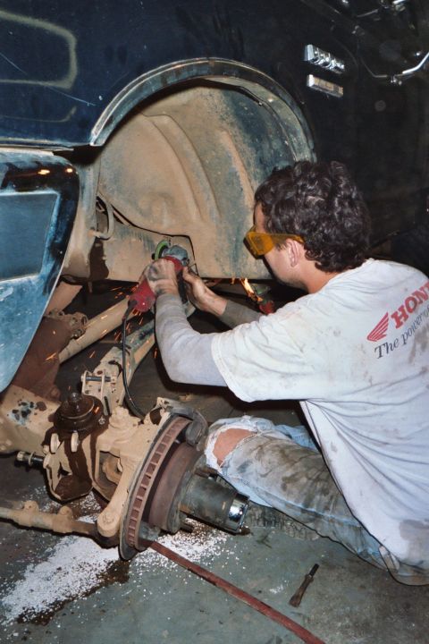 1988 Ford Bronco - A mechanic uses an angle grinder on the wheel well of a 1988 Ford Bronco, likely for a lift modification.