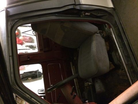 1988 Ford Bronco II - View of the interior of a vehicle, showing the seats and steering wheel, with items visible through the open door.