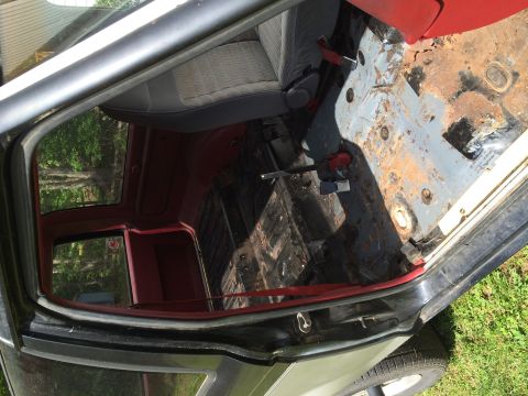 1988 Ford Bronco II - The interior of this vehicle shows significant rust on the floor and worn seats.