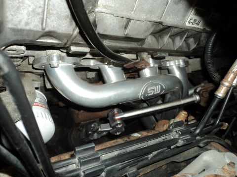 2004 Mercury Grand Marquis - Close-up of an engine's exhaust manifold, showing the SW logo and surrounding components.