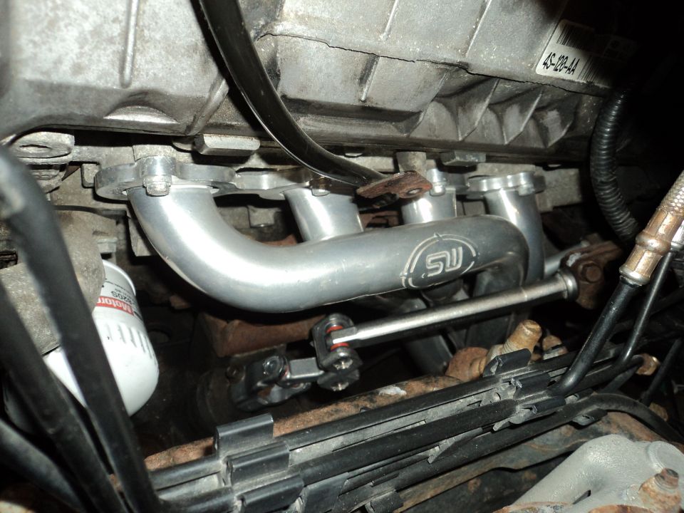 Engine exhaust manifold with SW logo, oil filter, and wiring