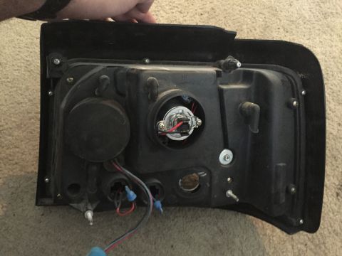 1996 Ford Bronco - Rear view of a vehicle headlight assembly, showing the bulb socket and wiring harness.