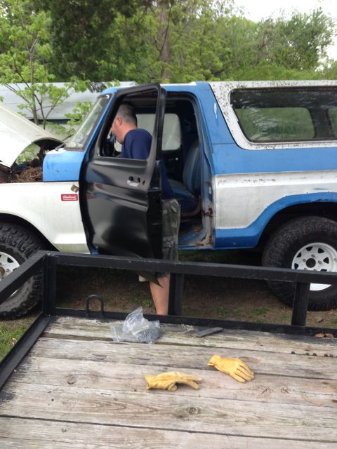 1979 Ford Bronco - A man works on a blue and white 1979 Ford Bronco, which has its hood and driver's door open.