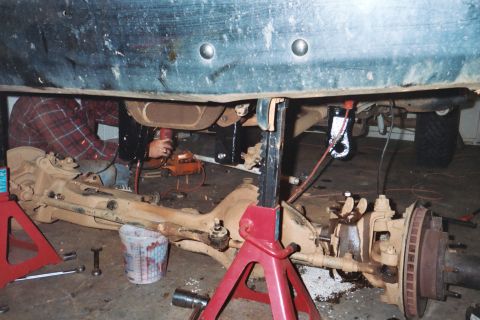 1988 Ford Bronco - A mechanic works on the undercarriage of a vehicle, focusing on the suspension and drivetrain components.