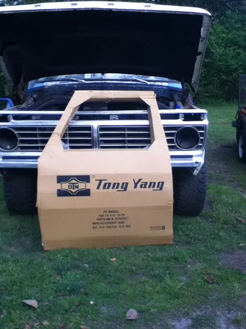 1979 Ford Bronco - Cardboard door cutout placed in front of a 1973 Ford F-Series truck with its hood open.